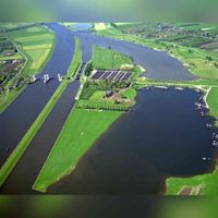 Luchtfoto van de Lek met de stuw, de schutsluis en de steenfabriek de Ossenwaard te Hagestein in de gemeente Vianen. Vanuit het oosten gezien op donderdag 3 mei 1990. De plaatsnaam Vianen (Via) betekend 'Vestigingsplaats aan of bij de weg (via)'. Bron: Het Utrechts Archief, catalogusnummer: 50747.