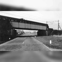 Gezicht op de Provincialeweg (Schalkwijkseweg) tussen Houten en Schalkwijk met het viaduct van de spoorlijn Utrecht-'s-Hertogenbosch in 1960. Deze brug werd in de jaren 70 va de vorige eeuw door de Provinciale Waterstaat van Utrecht 'De Poel' genoemd. Bron: Het Utrechts Archief, catalogusnummer:	 839248.