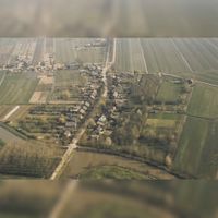 Luchtfoto van het dorp Tull vanuit het zuiden. Onderaan de foto het Inundatiekanaal, in het midden de Lange Uitweg met rechts de Achterdijk en links de Waalseweg in ca. 1990. Bron: Regionaal Archief Zuid-Utrecht (RAZU), 353.