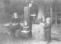 Bij de drinkbak voor de koeien en de houten pomp waar de kinderen zich best vermaken. Van links naar rechts: Wilhemina, Neeltje, Margje en Gerrit Feijth. In de boomgaard naast een boom staat vader Feijth.