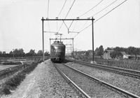 Afbeelding van een elektrisch treinstel mat. 1936 van de N.S. op de spoorlijn Utrecht-Arnhem nabij Lunetten. Met links en rechts op de achtergrond het Rijndijkje met de gedoogspoorwegovergang. Links naast het treinstel is nog een wit waarschuwingsbordje te zien. Bron: Het Utrechts Archief, catalogusnummer: 836270.