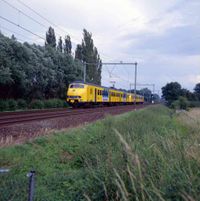 Gezicht richting het oosten op een mat 64 treinstel komend uit de richting van Arnhem richting Utrecht Centraal gezien bij de spoorwegovergang in de Mereveldseweg in mei - juni 1997. Bron: Het Utrechts Archief, catalogusnummer: 852439.