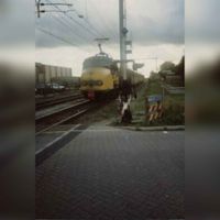 De toenmalige spoorwegovergang van de Staatslijn H (Utrecht-'s-Hertogenbosch) in de Odijkseweg (Standerdmolen)-Vlierweg (1868-2000) met de passerende mat. '54 treinstel in de richting van Geldermalsen in 1985-1990 Bron: Regionaal Archief Zuid-Utrecht (RAZU), 353.