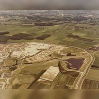 Luchtfoto gezien vanuit het zuiden van Houten Noordoost met de Kooikersplas en de bouw van de buurten De Velden en De Sloten. Rechts de oostelijke Rondweg rond 1981-1982. Bron: Regionaal Archief Zuid-Utrecht (RAZU), 353.