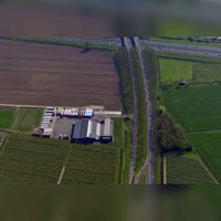 Luchtfoto gezien vanuit het westen met de Utrechtseweg lopend over de rijksweg A27 met links het transportbedrijf op nr. 19. Uiterst rechts de Warmoesgraaf. Foto: Slagboom en Peeters luchtfotografie B.V..