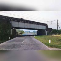 Gezicht op de Schalkwijkseweg tussen Houten en Schalkwijk met het viaduct van de spoorlijn Utrecht-'s-Hertogenbosch in 1960. Digitaal ingekleurd. Bron: Het Utrechts Archief, catalogusnummer: 839248.