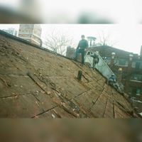 Dakdekkers op een hellend dak in de Verenigde Staten die een dak afscheuren. Bron: EN Roofer Wikipedia Victor Grigas - Fotografie door Victor Albert Grigas (1919-2017).