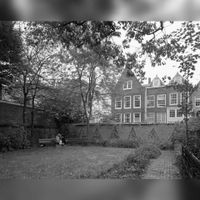 Gezicht in Flora's Hof te Utrecht; waarvan de toegang tussen de huizen Servetstraat 5 en 7 is gelegen, met de westelijke tuinmuur uit het oostnoordoosten en op de achtergrond de achterzijde van de huizen aan de Lichte Gaard op zaterdag 18 oktober 1980. Bron: Het Utrechts Archief, catalogusnummer: 70158.