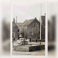 De fontein en vlaggenmast op het Plein met op de achtergrond enkele panden aan de westzijde van het Plein in het voorjaar van 1958. Bron: Regionaal Archief Zuid-Utrecht (RAZU), 353, 40486, 47.