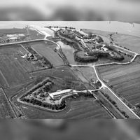 Luchtfoto van de Stelling van Honswijk met Fort Lunet aan de Snel gezien vanuit het noordoosten uit in de jaren zeventig van de vorige eeuw. Links de boerderij De Stenen Kamer. Rechts het Inundatiekanaal. Bron: RCE, beeldbank.