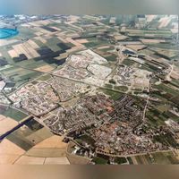 Luchtfoto gezien vanuit het westen op Houten Noordwest in onteikkrlinh met beneden de Utrechtseweg en bovenaa Houten Noordoost in ontwikkeling in 1982. Collectie gemeente Houten.