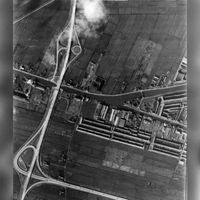 Verticale luchtfoto van het zuidelijke deel van de polder Hoograven (onder) en Westraven (boven) te Jutphaas. Links de Rijksweg 12, in het midden het Merwedekanaal en rechts de zuidelijke punt van de Rivierenwijk te Utrecht. N.B. De polders Hoograven en Westraven behoren sinds 1 jan. 1954 tot de gemeente Utrecht op 2 maart 1945. N.B. De straatnaam Rijksweg 12 is na 1976 gewijzigd in A12. Bron: HUA, catalogusnummer: 85093.